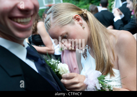 Teenage girl épingle un petit bouquet de fleurs sur sa date d'une high school prom Banque D'Images