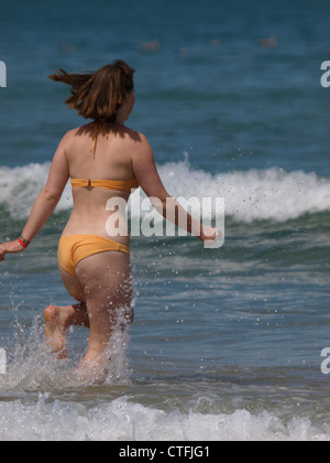 Jeune femme tournant dans la mer, Newquay, Cornwall, UK Banque D'Images