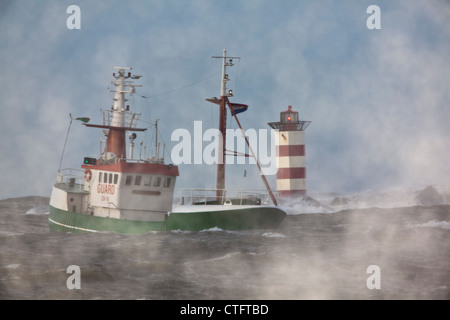 Les Pays-Bas, IJmuiden, tempête. Les vagues déferlent contre phare ou phare. Le navire. Banque D'Images