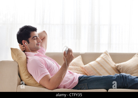 Jeune homme détendu l'écoute de musique à la maison Banque D'Images