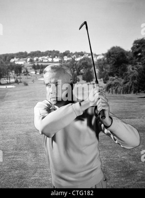 1960 MAN PLAYING GOLF FRAPPER BALLE DE GOLF CLUB DE FER AVEC FAIRWAY Banque D'Images