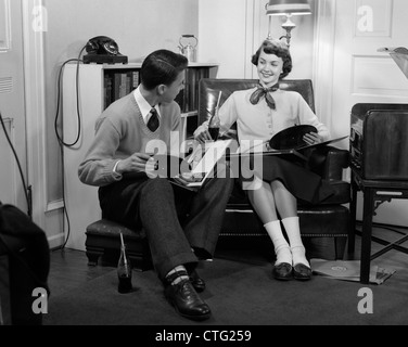 Années 1950, TEEN BOY & GIRL SITTING IN LIVING ROOM BOISSON & À ÉCOUTER DES DISQUES Banque D'Images