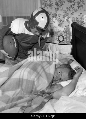 1950 garçon en uniforme de football se réveiller tôt le matin PÈRE Banque D'Images