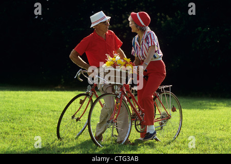 1980 Couple âgé AVEC DES BICYCLETTES À LA RECHERCHE À L'un l'autre Banque D'Images