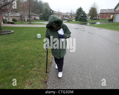 Une personne âgée retraitée dans ses années 90 marcher dans le froid venteux transportant courrier envois en Ontario Canada Kathy DEWITT Banque D'Images