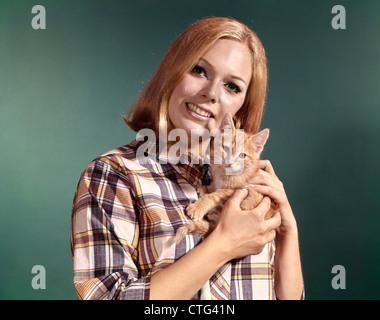 1960 PORTRAIT YOUNG BLONDE WOMAN PORTER Chemise à carreaux MADRAS CHEF HOLDING RED TABBY KITTEN ANIMAL Banque D'Images