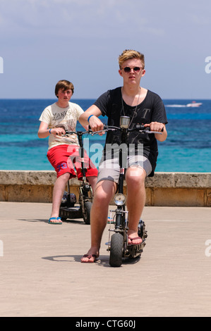 Deux adolescents sur les scooters électriques par la mer pendant les vacances en espagne Banque D'Images