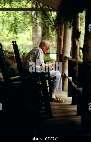 1980 PERSONNES ÂGÉES SENIOR MAN SITTING ON PORCH EN FAUTEUIL À BASCULE Banque D'Images