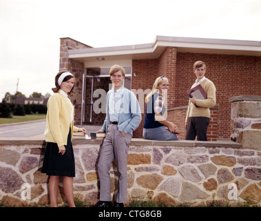 1960 ÉTUDIANTS SUR LE CAMPUS DE L'ADOLESCENCE GARÇONS FILLES DES COUPLES PAR GROUPE MUR DE PIERRE RETRO Banque D'Images