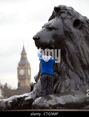Escalade sur une garçon Lion Landseer à Trafalgar Square Banque D'Images