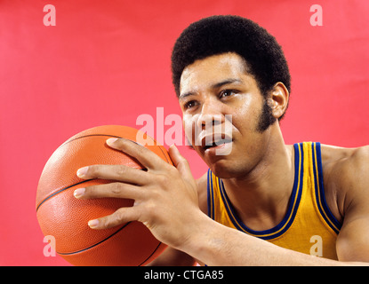 1970 AFRICAN AMERICAN MAN BASKETBALL PLAYER HOLDING BALL Banque D'Images