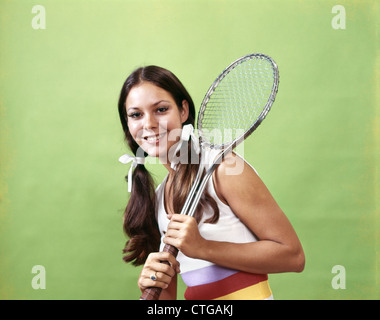 1970 JEUNE BRUNETTE WOMAN SMILING HOLDING METAL RAQUETTE DE TENNIS LOOKING AT CAMERA Banque D'Images
