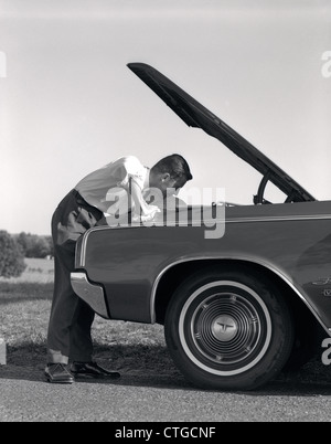 1960 Vue de côté de l'homme en chemise et cravate À SOUS LE CAPOT DE LA VOITURE S'ARRÊTA SUR LE BAS-CÔTÉ DE LA ROUTE Banque D'Images