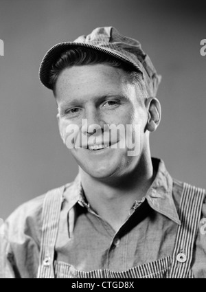 1940 PORTRAIT OF SMILING MAN WEARING DE COL BLEU, bretelles et ingénieur HAT LOOKING AT CAMERA Banque D'Images