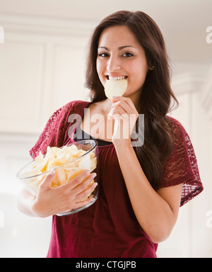 Mixed Race woman eating potato chips Banque D'Images