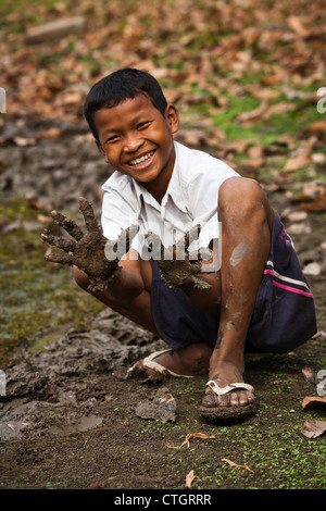 Smiling Cambodian garçon montre mains boueuses en creusant à la pêche vers pour Angkor Wat appâts populaires un site du patrimoine mondial de l'UNESCO Banque D'Images