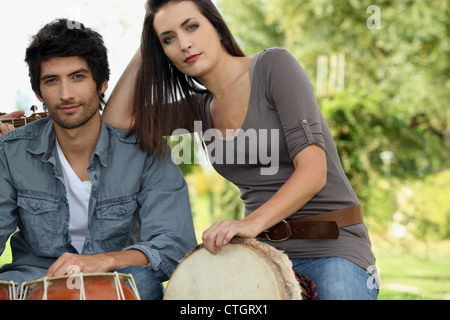 Couple playing bongo drums outdoors Banque D'Images