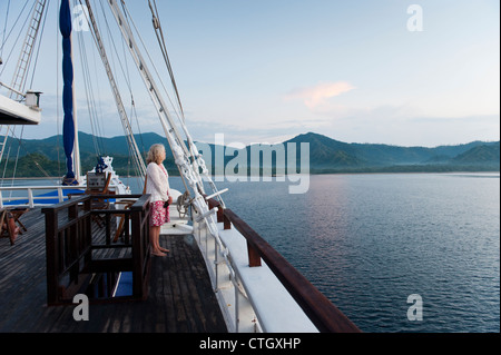 À bord du 'Ombak Putih' un Pinisi goélette traditionnelle en bois, l'île de Komodo est visible au lever du soleil dans l'arrière-plan. Banque D'Images