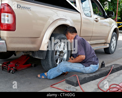 Changement de roue. Un mécanicien change une roue de voiture à l'aide d'un dispositif de levage hydraulique Banque D'Images