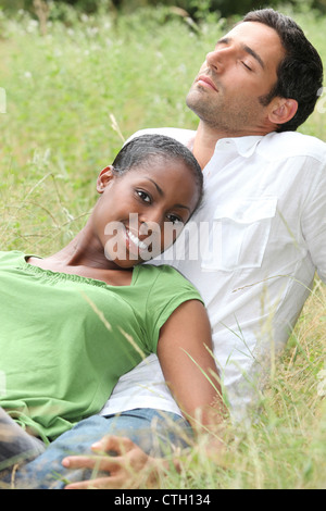 Couple mixte fixant dans un champ Banque D'Images