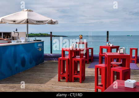 Compteur, chaises et parasol rouge avec la mer en arrière-plan sur la terrasse d'un bar sur la plage de Sardinero dans la ville de Santander, Cantabria, Banque D'Images