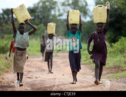 Les jeunes enfants du village de terminer leur journée de congé par la collecte de l'eau sale pour leurs familles dans le district de Lira d'Ouganda du Nord Banque D'Images