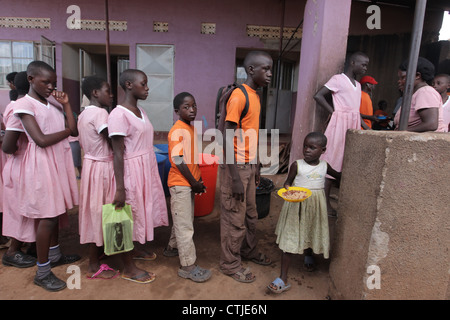 Les enfants de l'école pour leur déjeuner à l'ONG Enfants précieux financés par l'école primaire dans le Kosovo bidonville de la ville de Kampala Banque D'Images