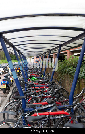 Les vélos garés infiltration en toute sécurité dans une aire de stationnement à l'extérieur d'une gare d'Angleterre. Banque D'Images