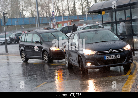 Taxi en attente d'une voiture pour s'éloigner d'un taxi un jour de pluie à l'extérieur d'une gare d'Angleterre. Banque D'Images