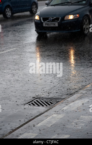 Verser de l'eau dans un égout sur le côté d'une route au cours d'une tempête en Angleterre. Banque D'Images