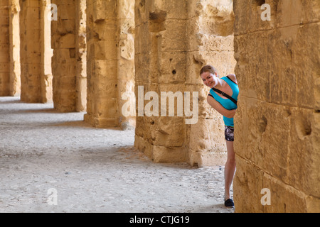 Jeune femme à la recherche de la colonne en démoli les murs anciens et des arches en amphithéâtre à El Djem, Tunisie Banque D'Images
