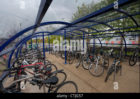 Les vélos garés infiltration en toute sécurité dans une aire de stationnement à l'extérieur d'une gare d'Angleterre. Banque D'Images