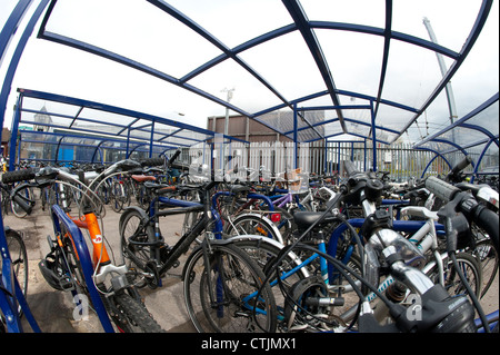 Les vélos garés infiltration en toute sécurité dans une aire de stationnement à l'extérieur d'une gare d'Angleterre. Banque D'Images