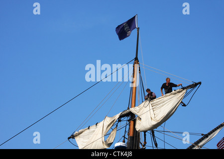 Deux marins fixant les voiles haut sur le mât sur une goélette en bois Banque D'Images