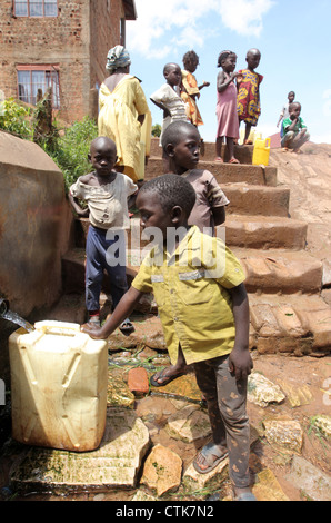 Les enfants de recueillir l'eau d'une source d'eau du gouvernement d'impur dans le Kosovo bidonville de la ville de Kampala en Ouganda. Banque D'Images