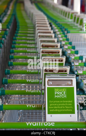 Rangée de chariots de supermarché Waitrose afficher 'brand : match' slogan. Banque D'Images