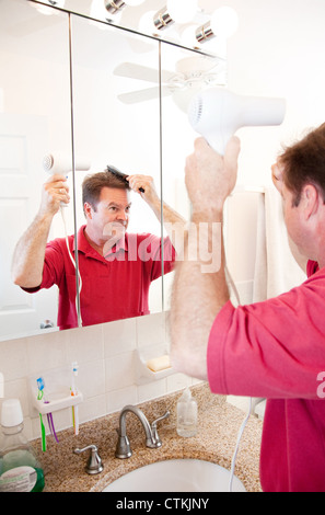 L'homme dans la salle de séchage coup ses cheveux. Partie de sa routine du matin. Banque D'Images