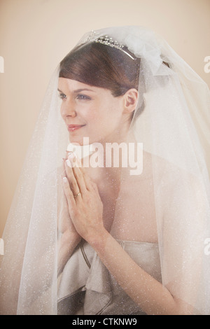 Une jeune mariée de porter un voile et diadème, mains jointes en prière Banque D'Images