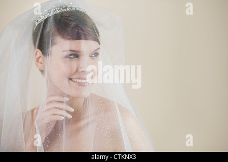 Une jeune mariée de porter un voile, diadème et à la recherche sur le côté smiling Banque D'Images