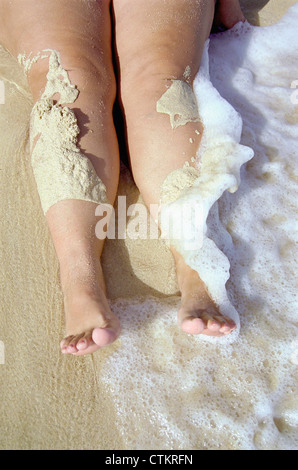 Une femme assise sur le sable. Banque D'Images