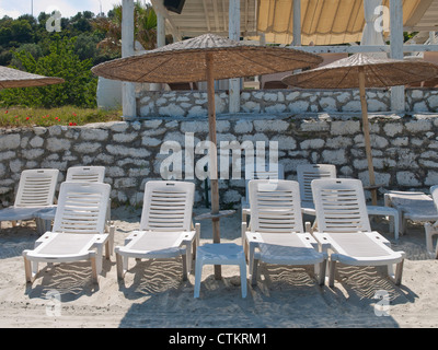 Soleil vide-longues et des parasols sur une plage grecque Banque D'Images