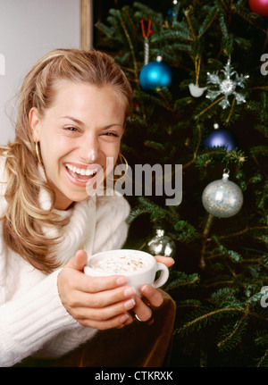 Une femme dans la 20's-30's (années 20-années 30) tenant une tasse de chocolat chaud avec de la crème fouettée. Banque D'Images