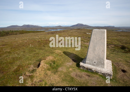 Isle of North Uist, Scotland. Trig point en haut de Beinn Langais à l'est avec l'île Skye dans l'arrière-plan lointain. Banque D'Images