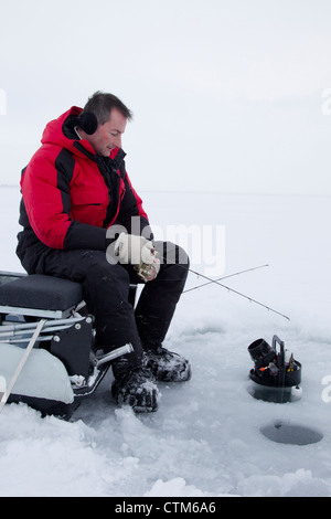 Pêcheur sur glace est assis sur un traîneau qu'il prennent pour le doré jaune. Banque D'Images