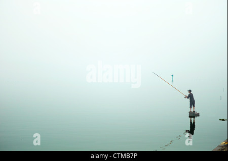 Un pêcheur solitaire sur le lac de l'ouest de la région de Hanoi, Vietnam Banque D'Images