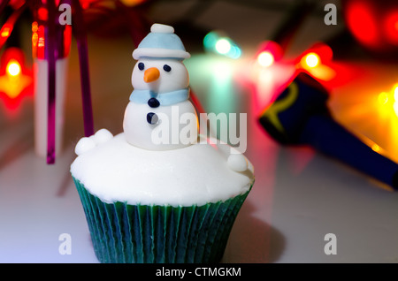 Close-up of a snowman cupcake with christmas fairy lights dans l'arrière-plan Banque D'Images