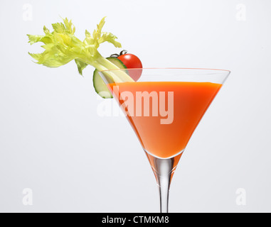 Un légume orange jus dans un verre a pied avec la garniture de légumes. De céleri, tranche de concombre et tomate cerise. Banque D'Images