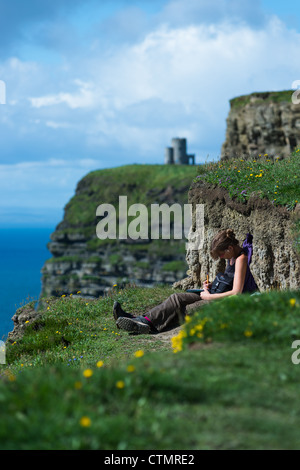 Une jeune femme jouit de la vue sur les falaises de Moher, comté de Clare, Irlande. Banque D'Images