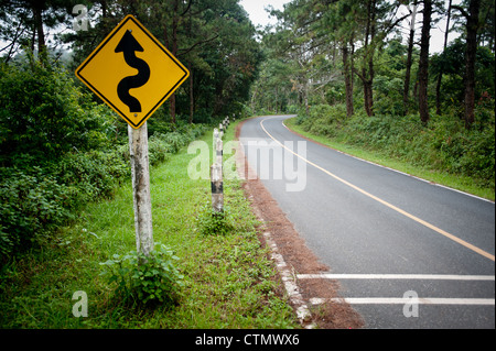 À vide, à travers la forêt avec road sign warning de lacets avant de Pai, le nord de la Thaïlande, la Thaïlande. Banque D'Images