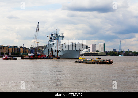 Le HMS Ocean amarré à Greenwich avec la ville de Londres derrière elle Banque D'Images